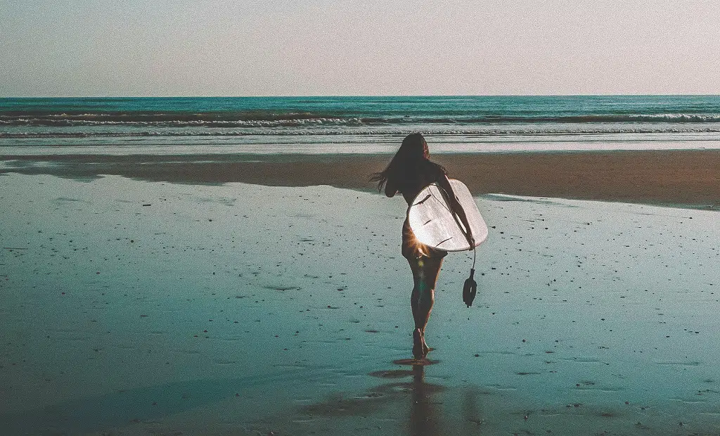 Pessoa a caminhar com uma prancha de surf na praia de Sesimbra